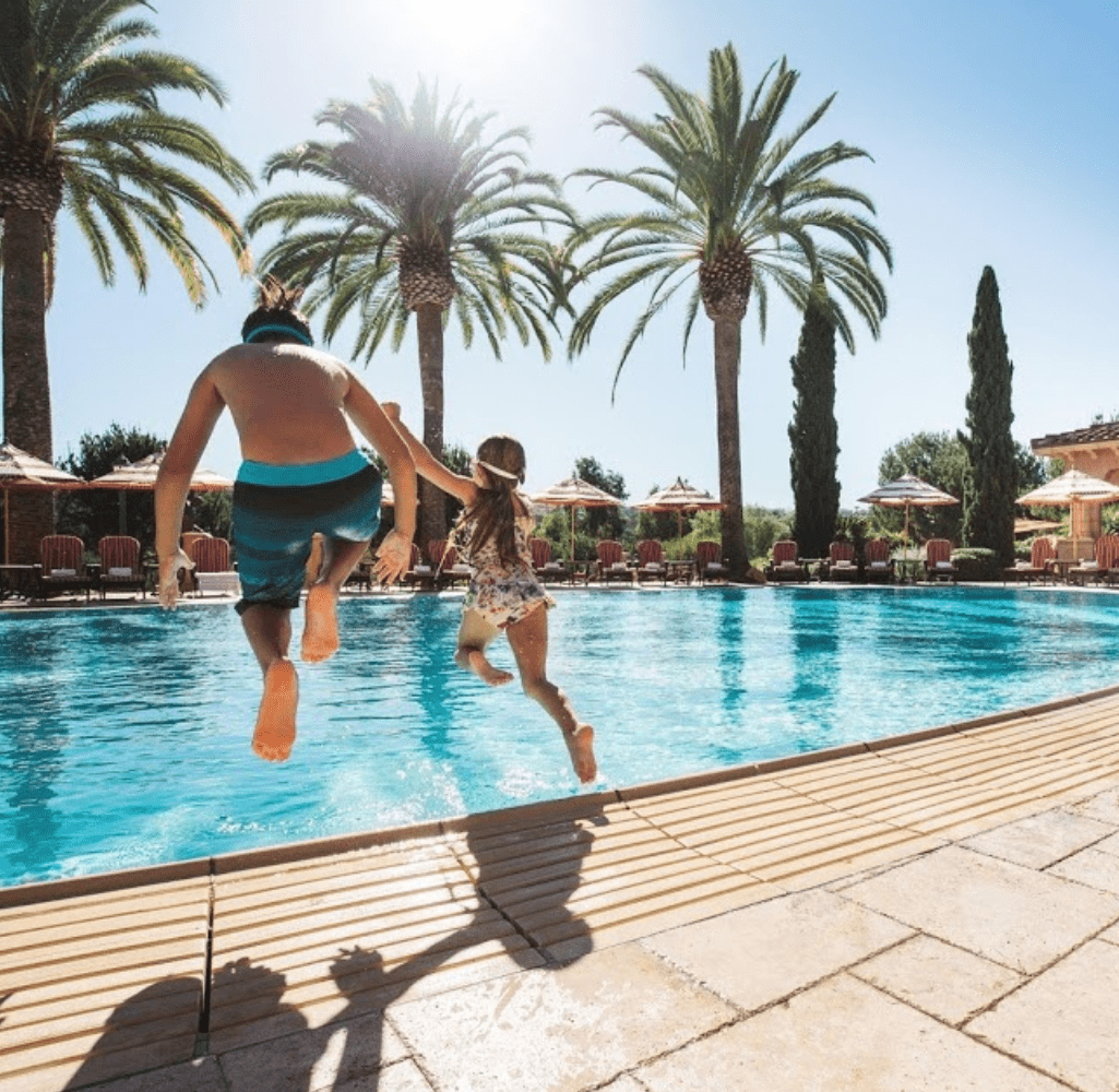 Fairmont Del Mar in San Diego California. Kids jumping into the pool with palm trees in the background
