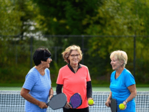 Members at Heritage Shores Golf Club standing in front of a pickleball net with their pickleball paddles and ball