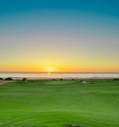 A sunset view of the golf course and ocean at AL Houara Golf Club in Morocco