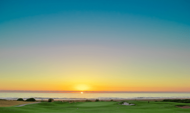 A sunset view of the golf course and ocean at AL Houara Golf Club in Morocco